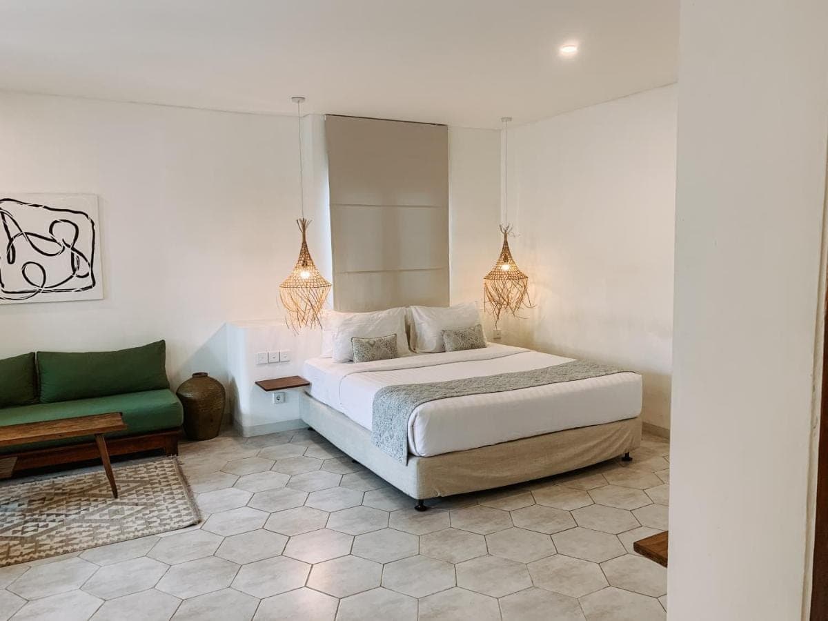 a bedroom with a bed and a green couch at Kresna By The Sea By Kresna Hospitality in Seminyak