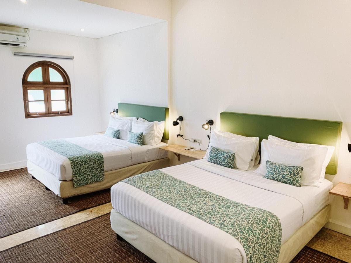 a hotel room with two beds and a window at Kresna By The Sea By Kresna Hospitality in Seminyak