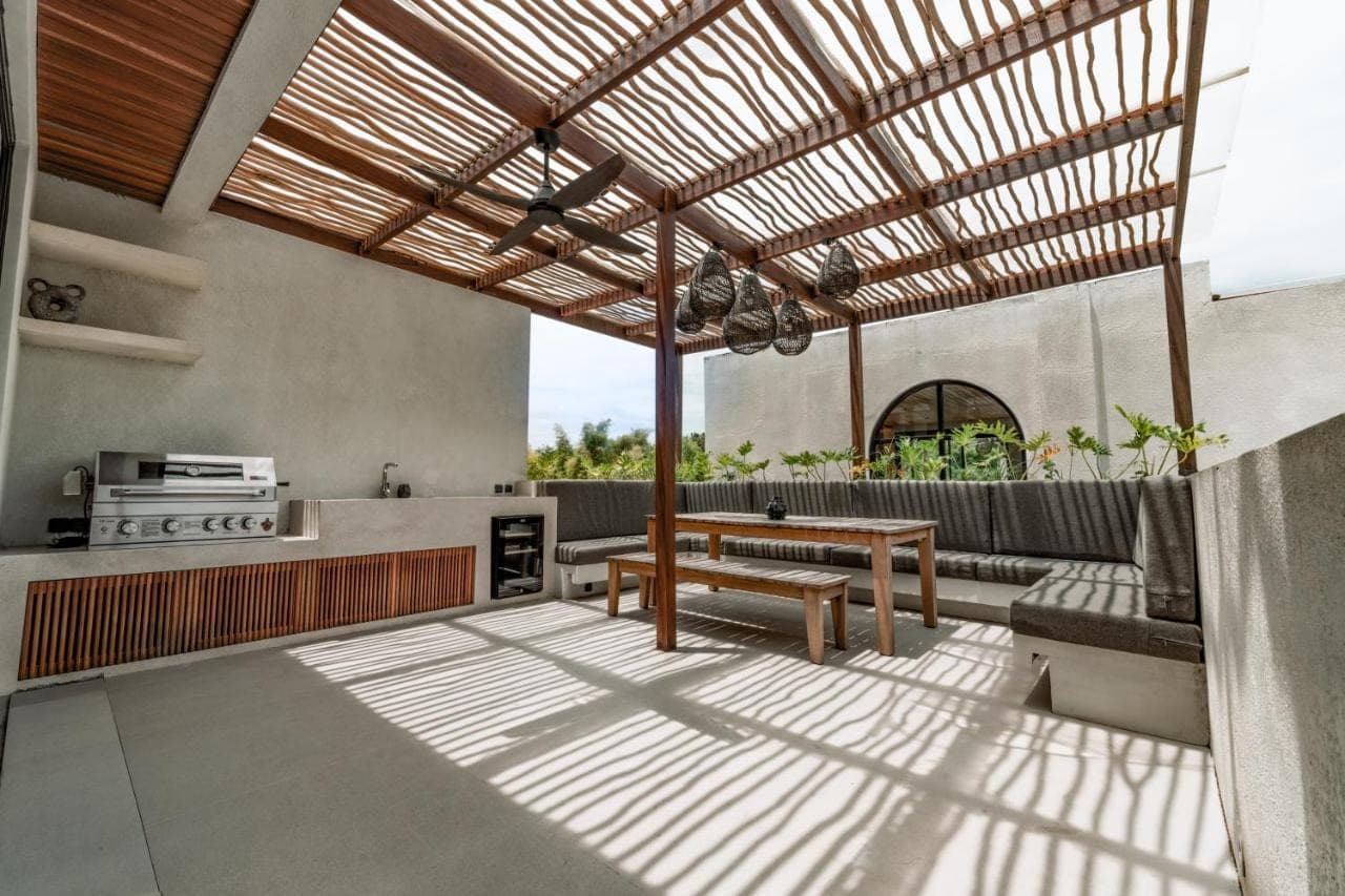 an outdoor kitchen with a wooden pergola at Adaya Boutique Villas in Uluwatu