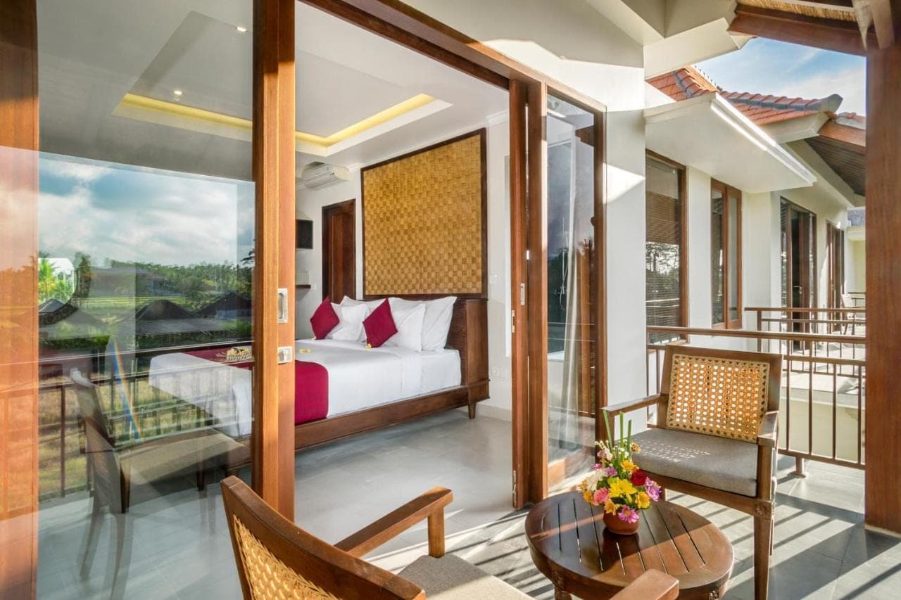 a bedroom with a balcony with a bed and a table at Bumi Muwa Ubud Katiklantang in Ubud