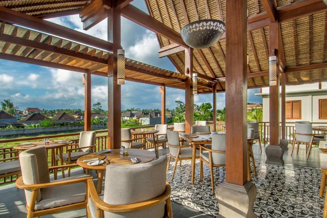a restaurant with tables and chairs on a roof at Bumi Muwa Ubud Katiklantang in Ubud