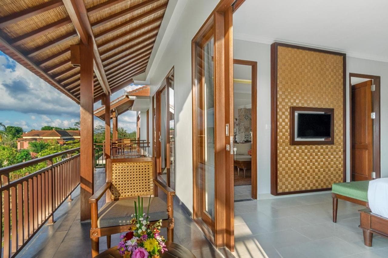 a room with a balcony with a bed and a television at Bumi Muwa Ubud Katiklantang in Ubud