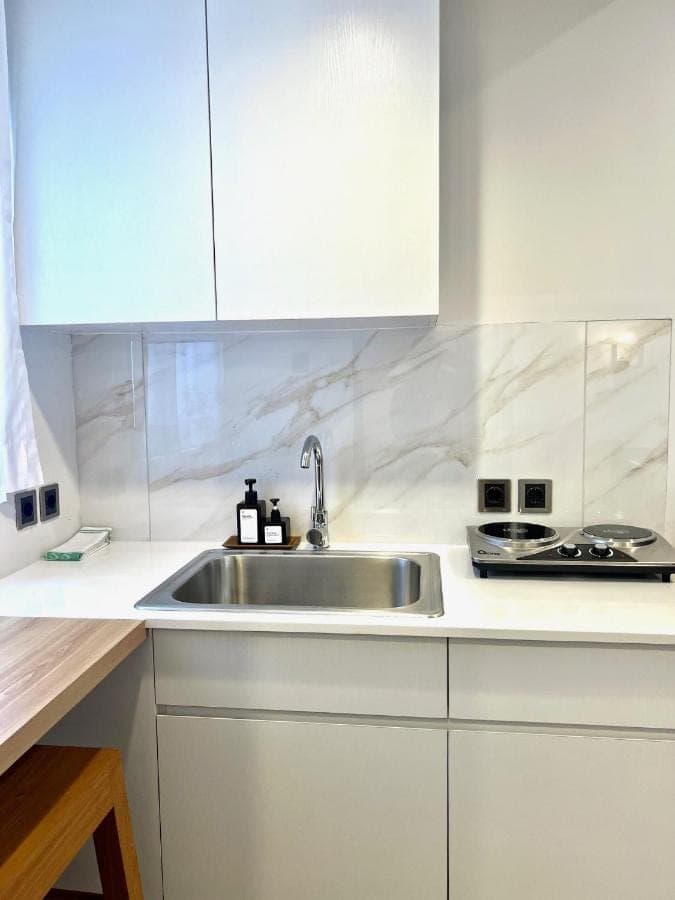 a kitchen with a sink and white cabinets at Charlie Guest House in Nusa Dua