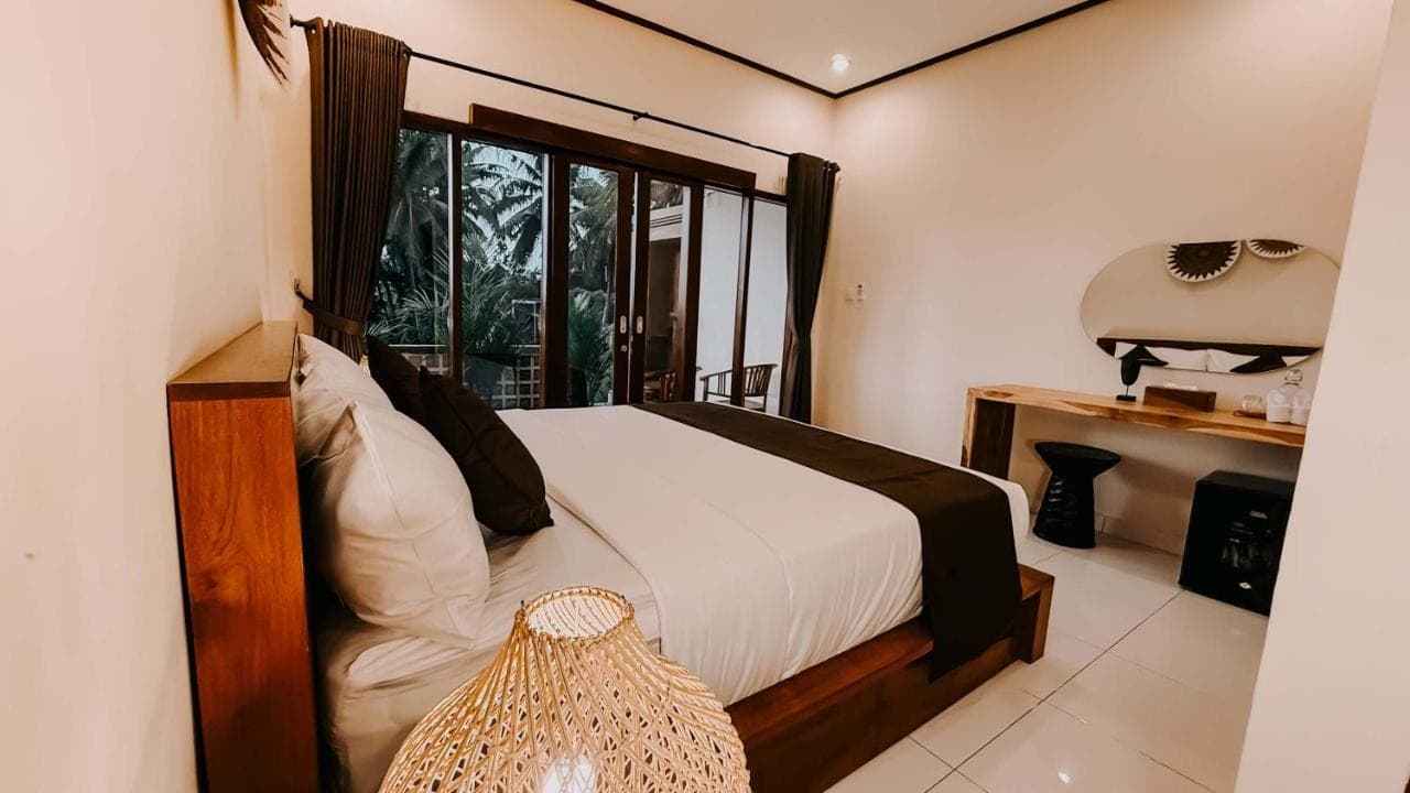a bedroom with a bed and a large window at Uma Mesari Ubud in Ubud