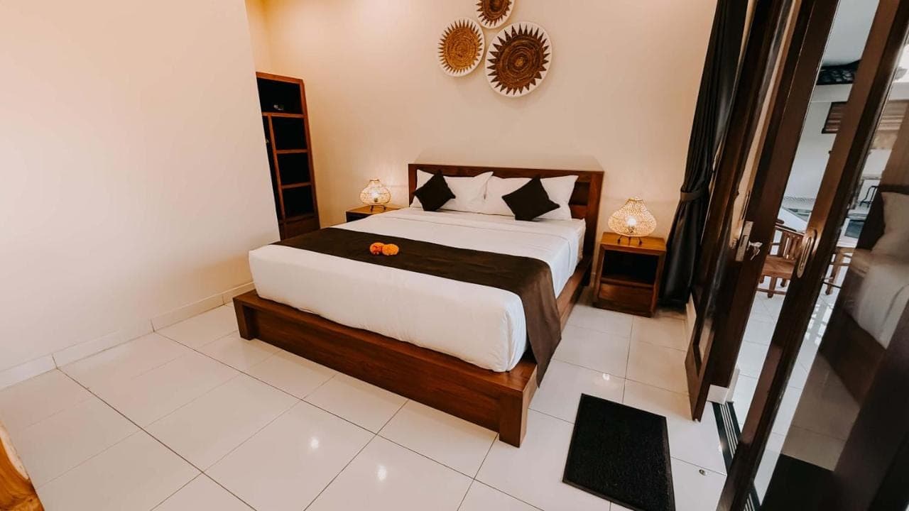 a bedroom with a large bed and a mirror at Uma Mesari Ubud in Ubud