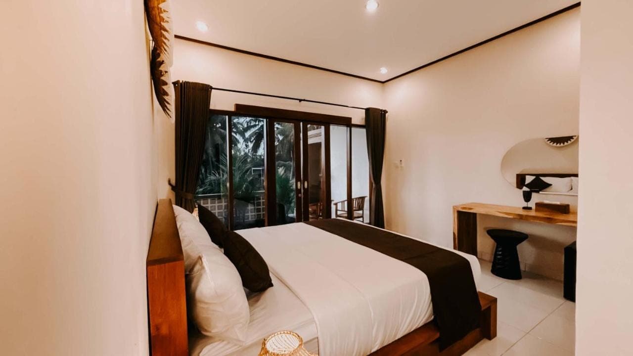 a bedroom with a bed and a desk and a window at Uma Mesari Ubud in Ubud