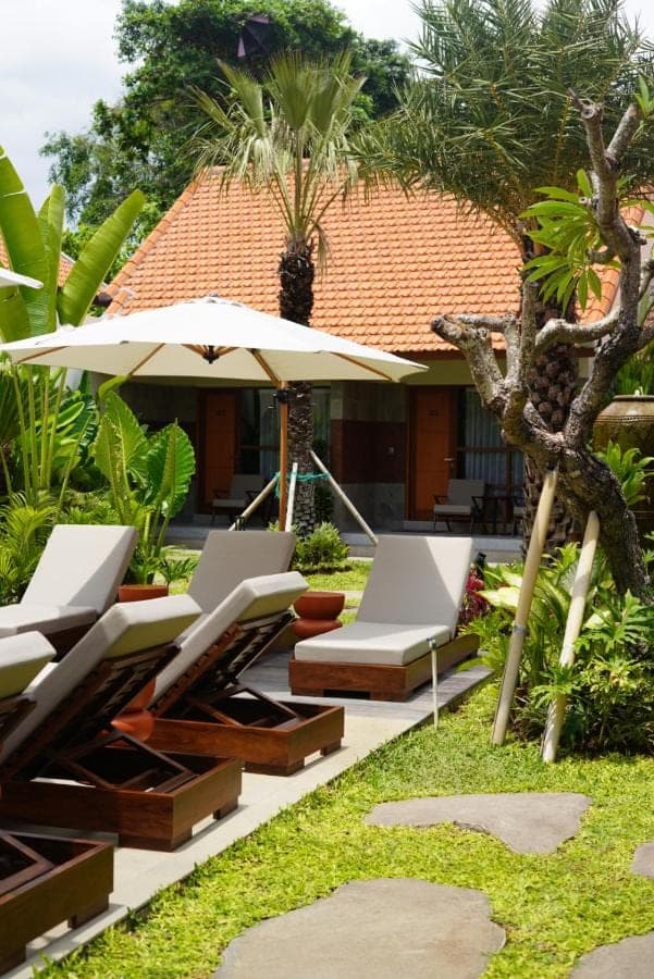 a patio with lounge chairs and an umbrella at Kesumasari Living in Sanur