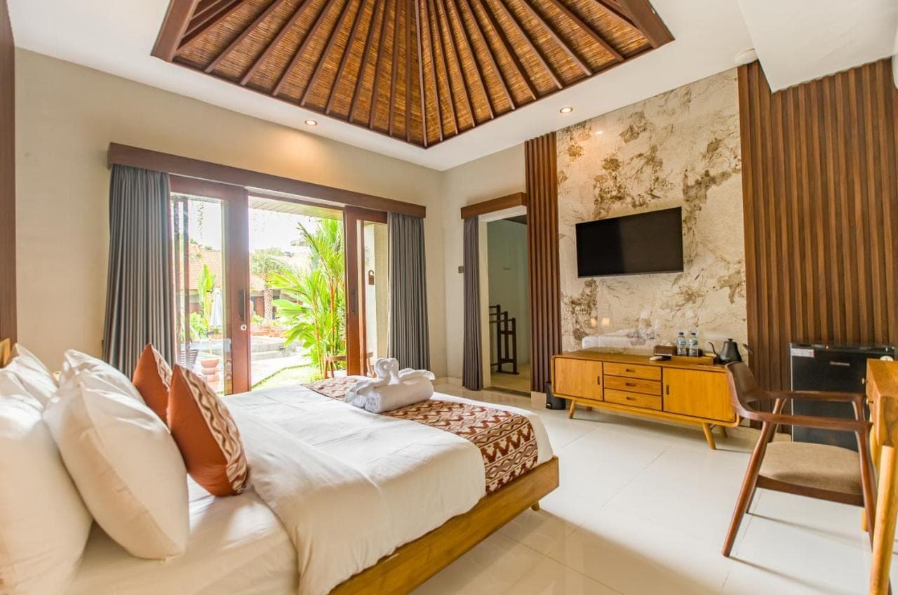 a bedroom with a large bed and a television at Kesumasari Living in Sanur