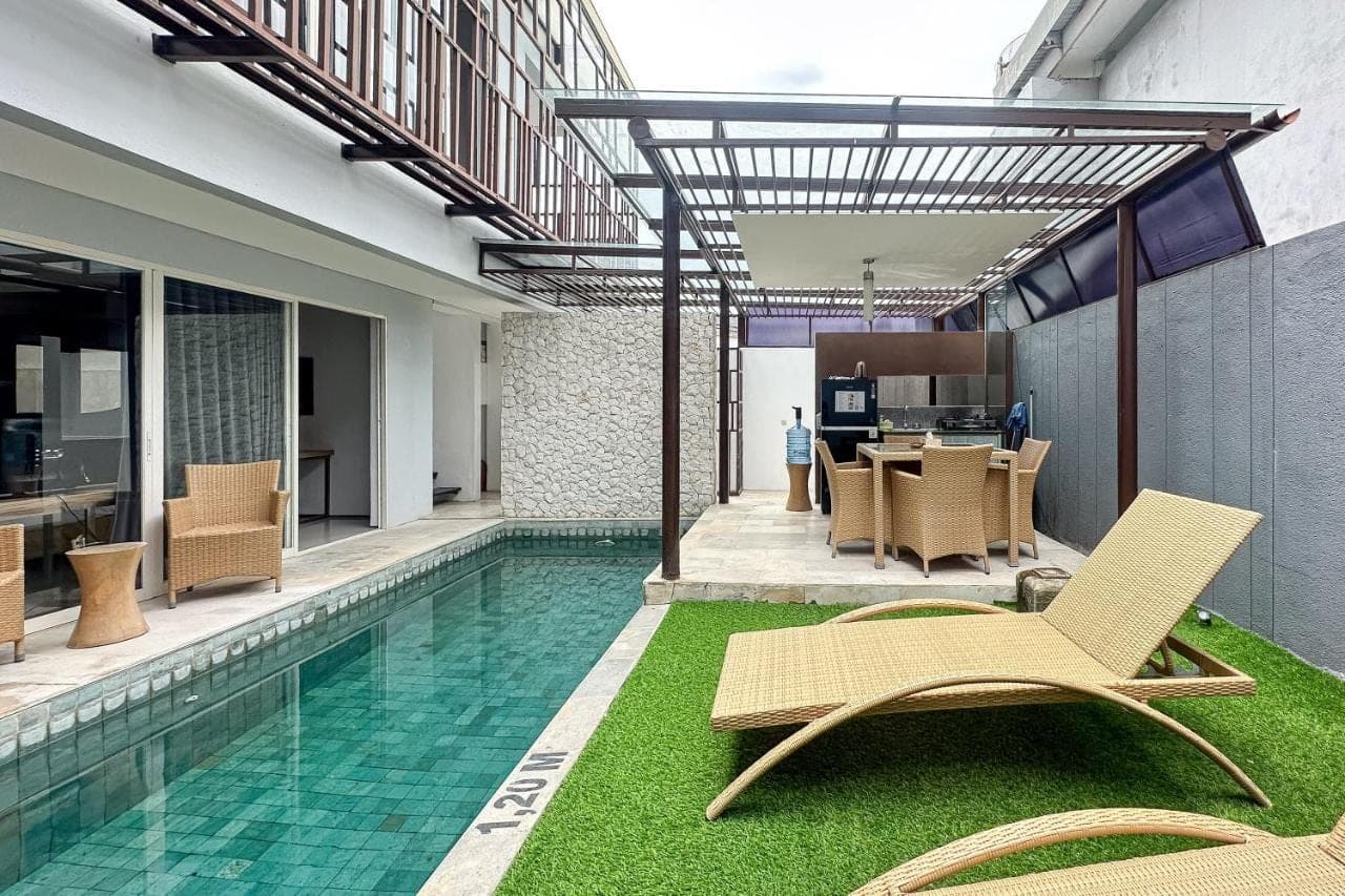 a swimming pool with chairs and a table and a house at Green Leaf Villa - 1 Bedroom pool Villa with Minimum Stay 2 Nights in Nusa Dua