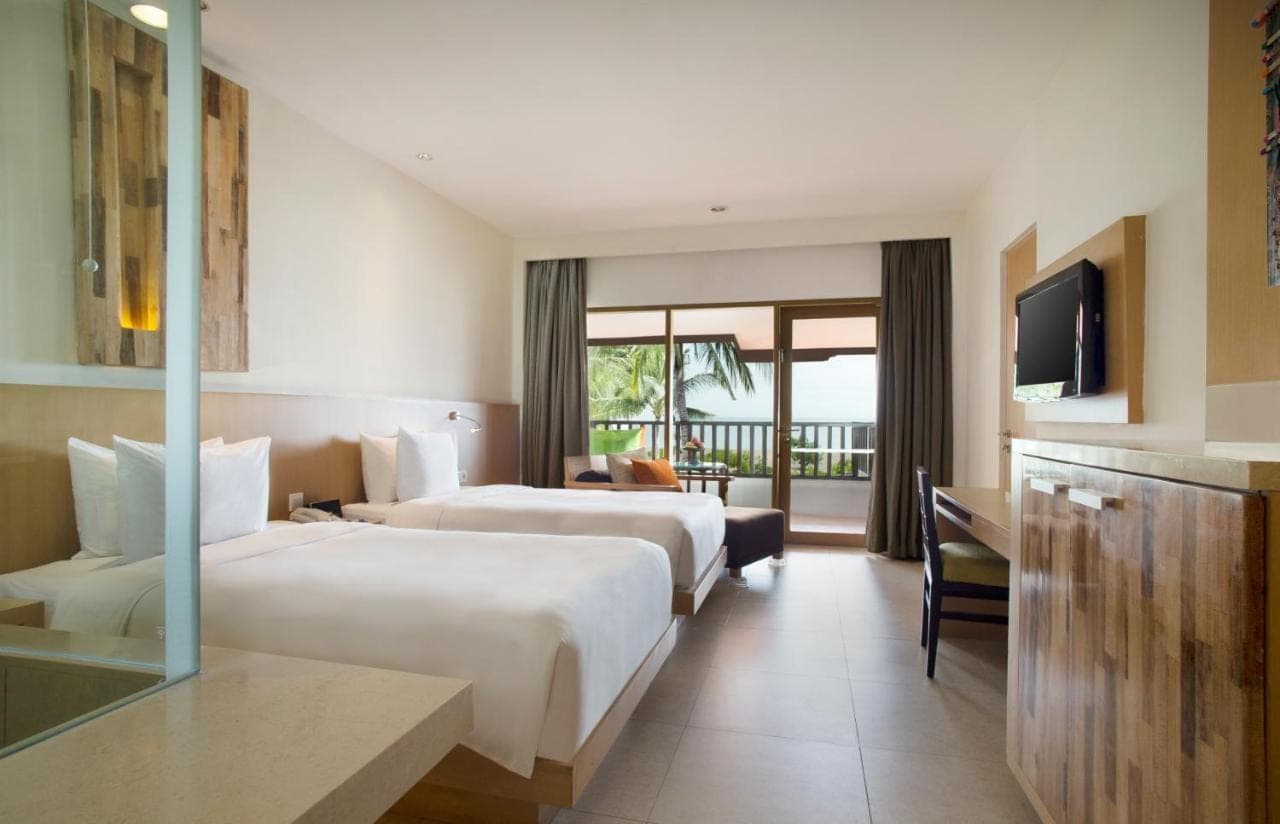a hotel room with two beds and a television at Holiday Inn Resort Baruna Bali by IHG in Kuta