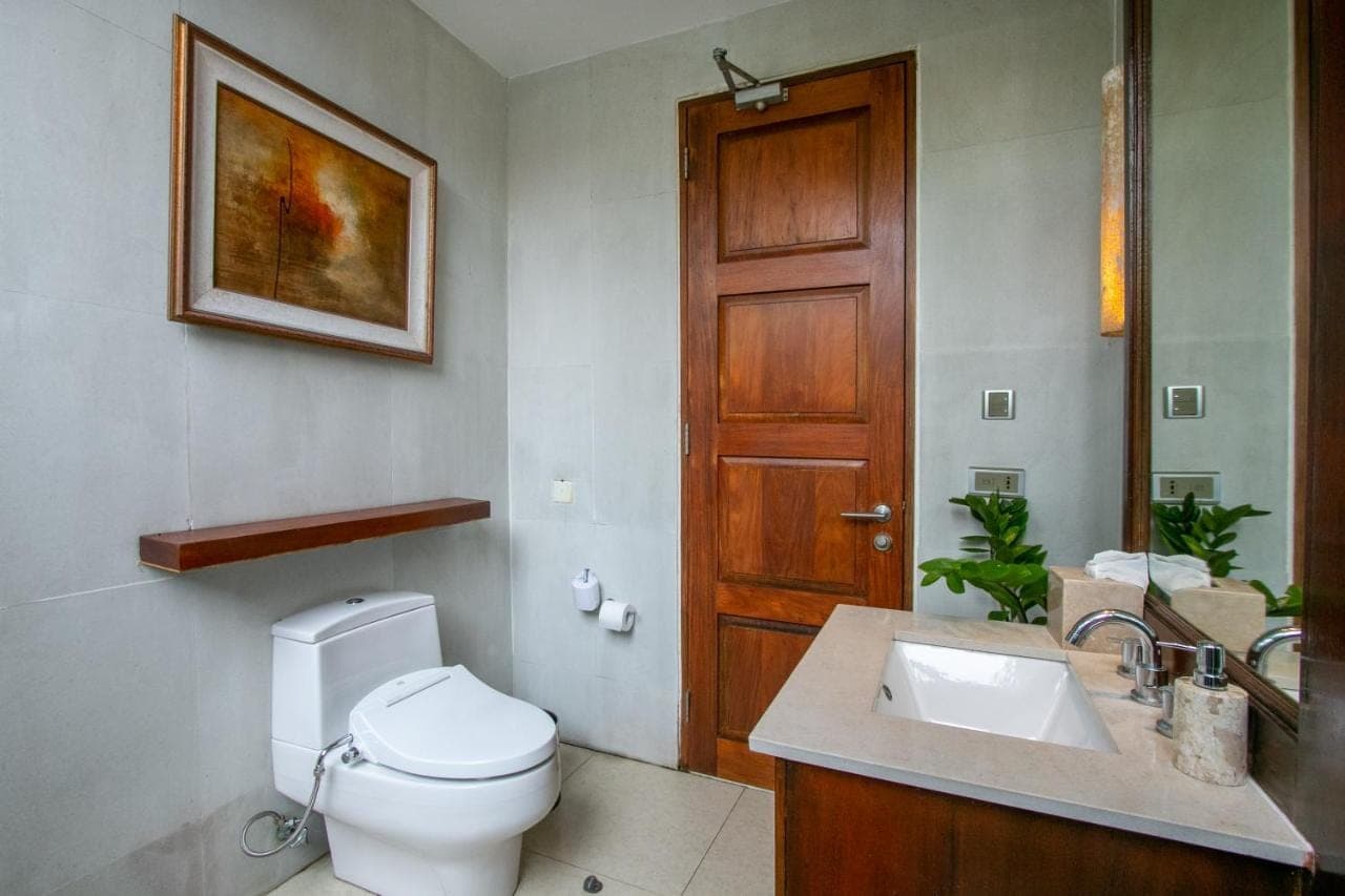 a bathroom with a toilet and a sink and a door at Holiday Inn Resort Baruna Bali by IHG in Kuta
