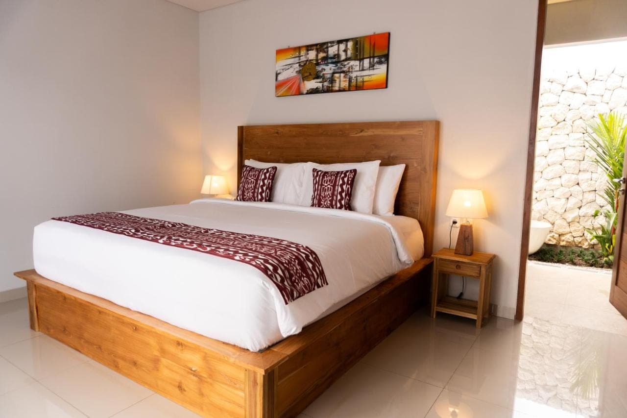 a bedroom with a large bed with a wooden headboard at The Ume Sidemen Villas in Sidemen