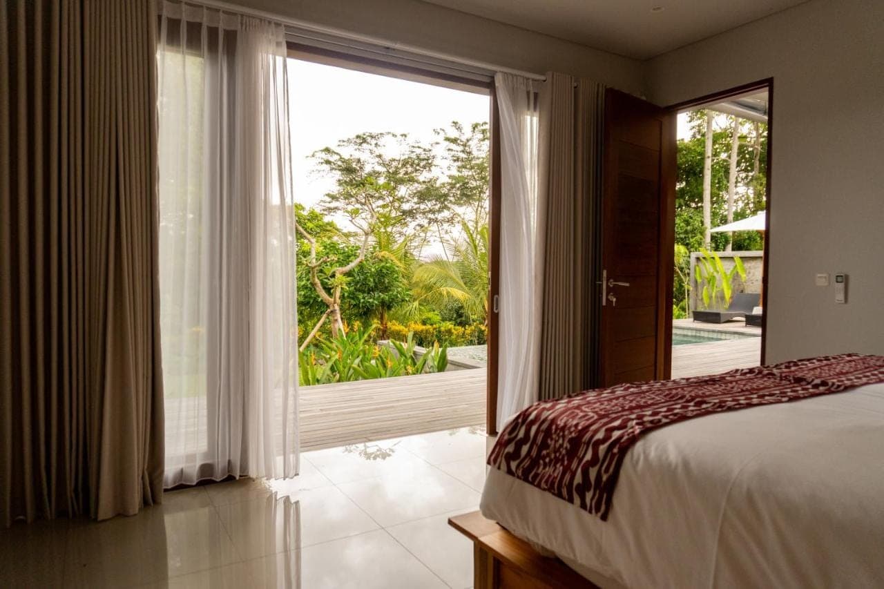 a bedroom with a bed and a large window at The Ume Sidemen Villas in Sidemen