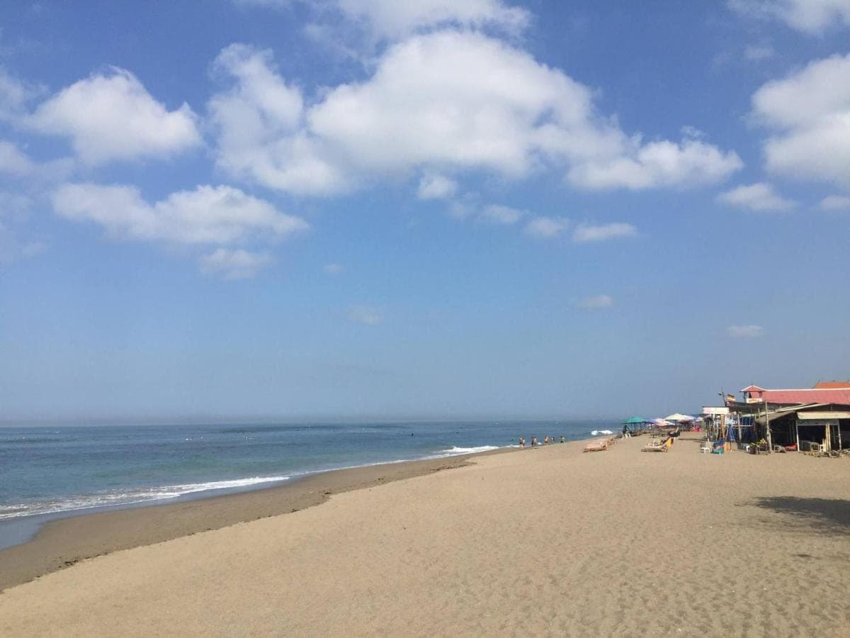 a beach with people sitting on the sand and the ocean at Atera Loft Canggu in Canggu
