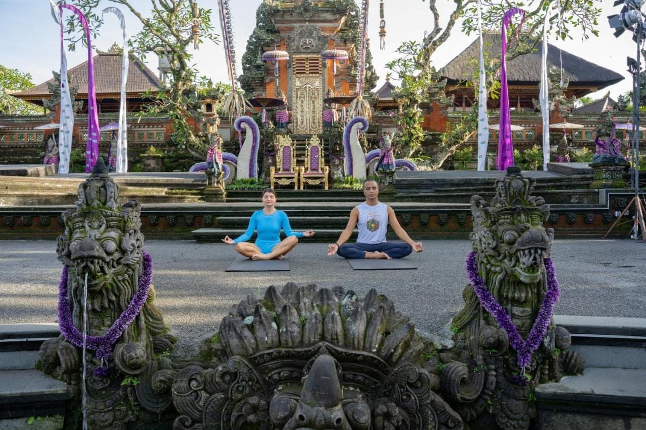 three people in aorative yoga pose in front of a temple at Puri Saraswati Dijiwa Ubud in Ubud