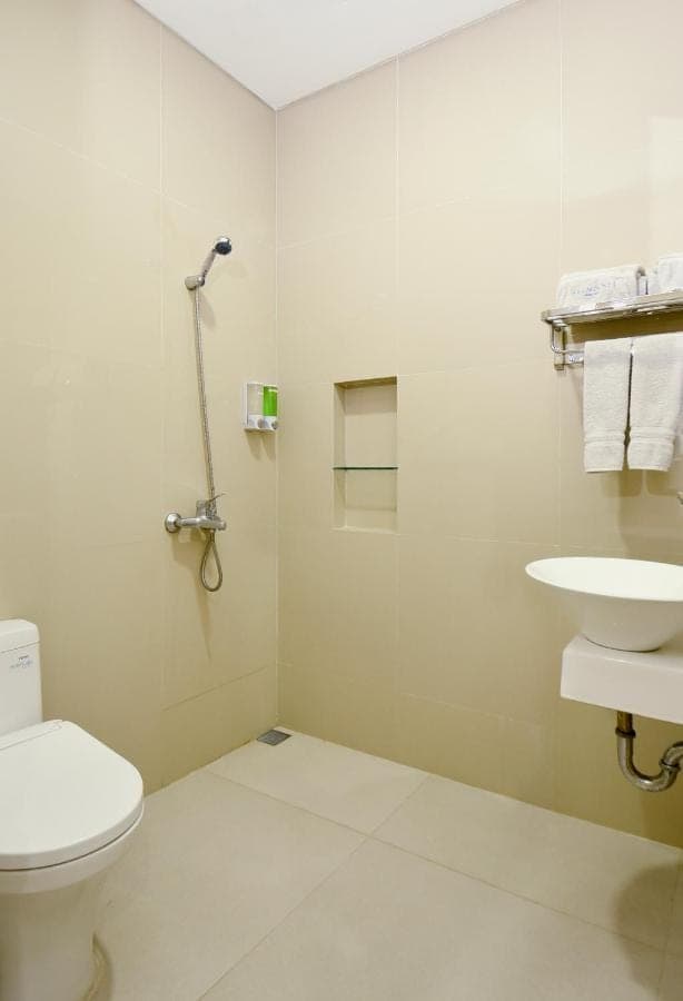 a white bathroom with a toilet and a sink at Seamount Hotel Amed in Amed