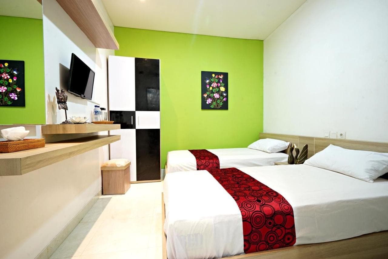 a bedroom with two beds with green walls at D'Pande Kuta in Kuta