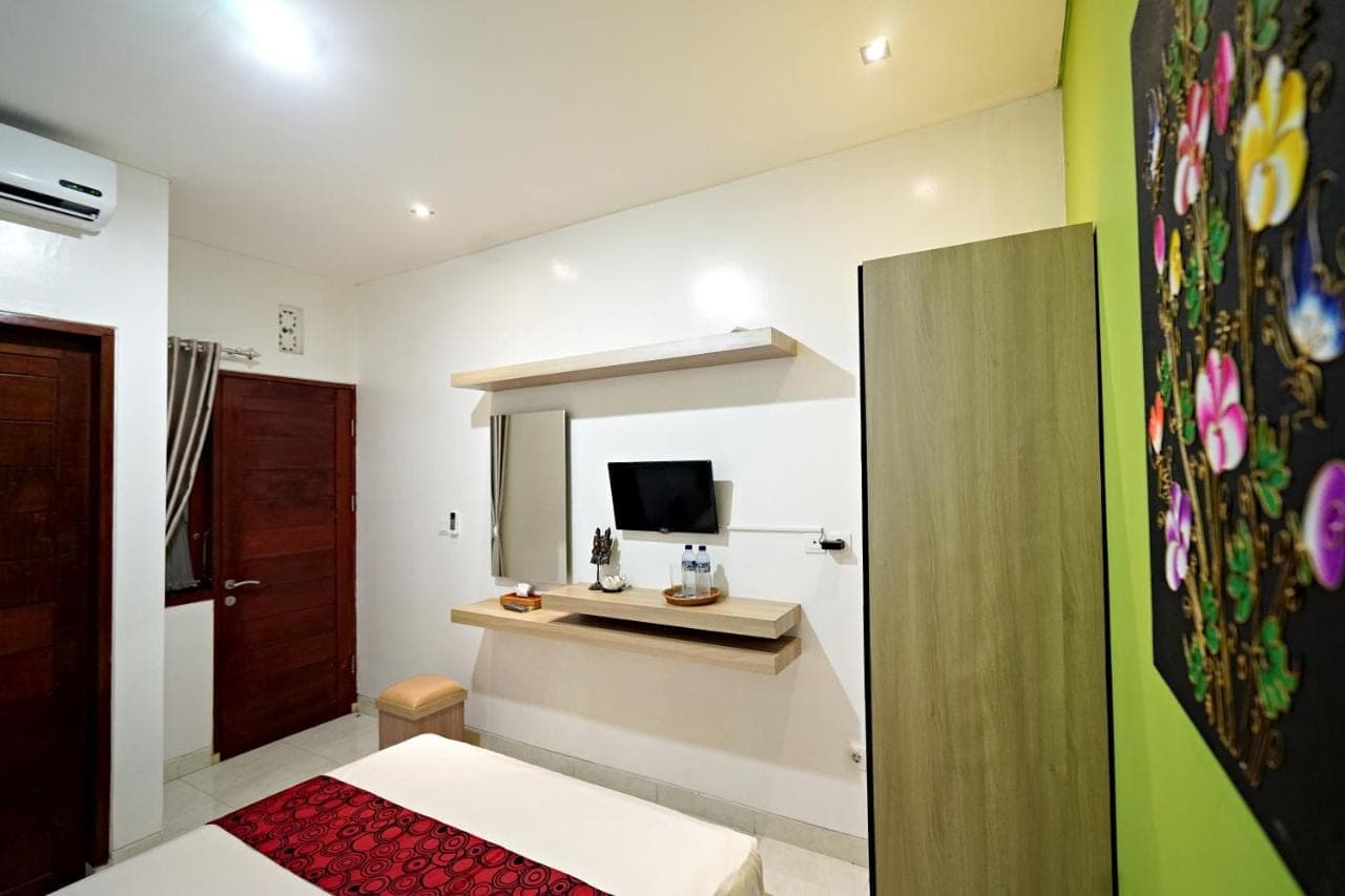 a room with a bed and a television in a room at D'Pande Kuta in Kuta