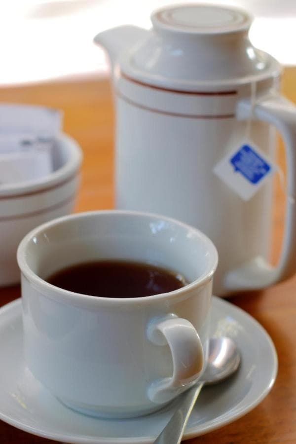 a cup of coffee on a plate with a spoon at Hotel Jati Sanur in Sanur