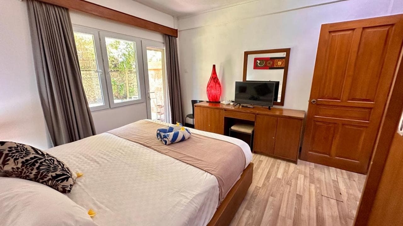 a bedroom with a bed and a desk with a television at Nattaya at the Jayakarta Bali in Seminyak