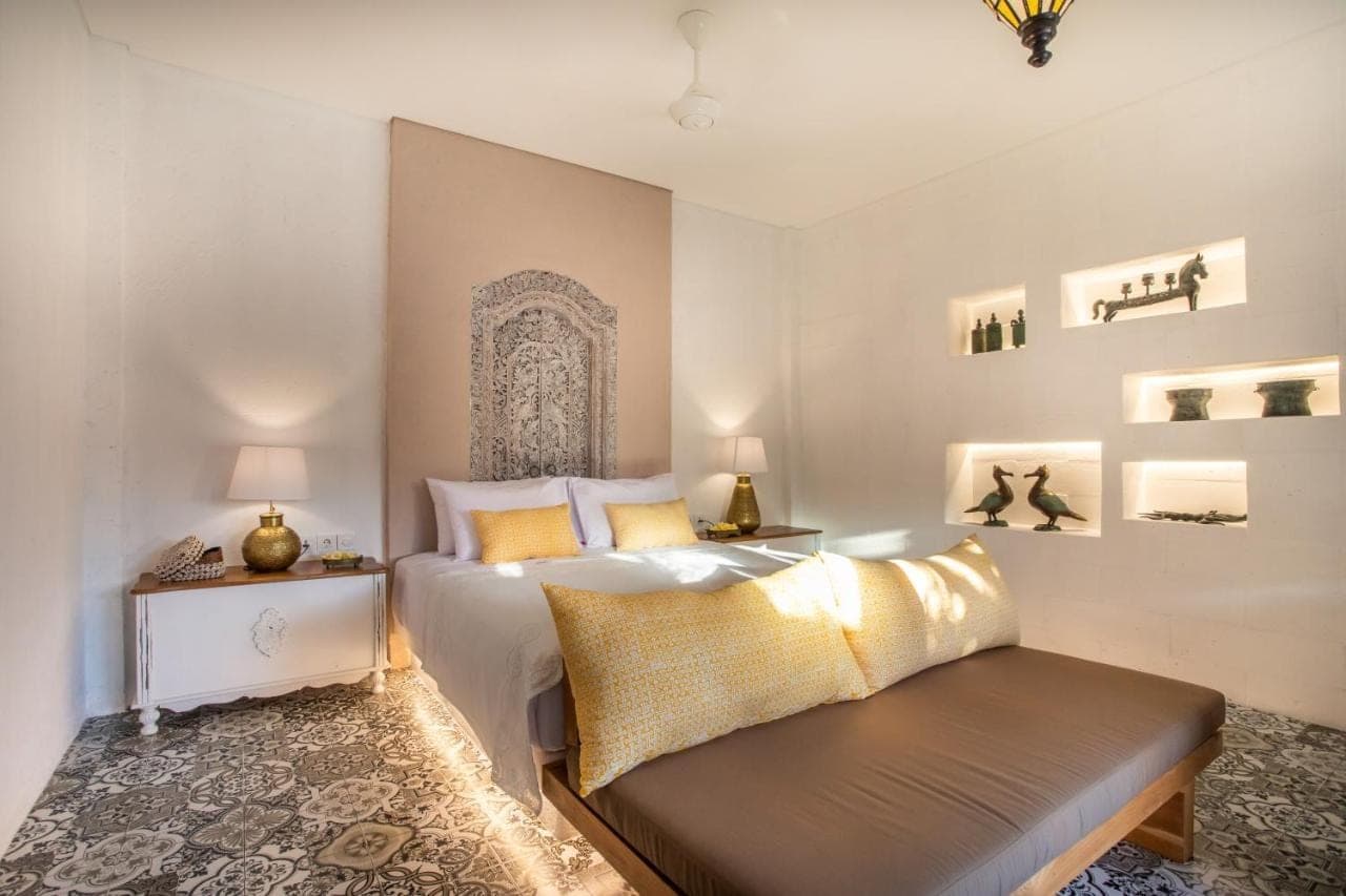 a bedroom with a bed and a bench in it at PinkPrivate Sanur - for Cool Adults Only in Sanur