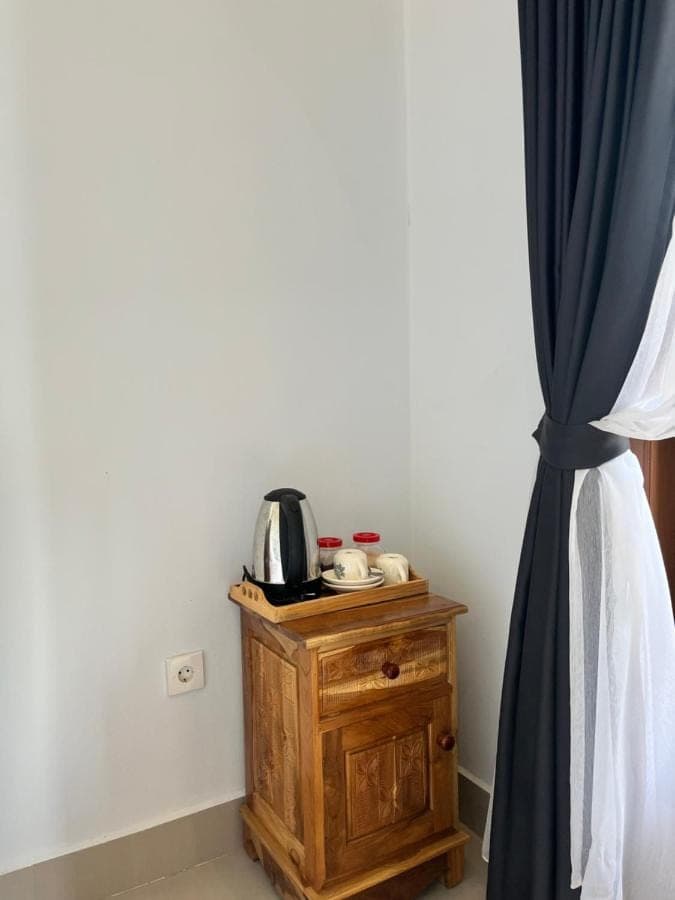 a room with a coffee maker on a wooden table next to a curtain at Krisna Double House in Sidemen