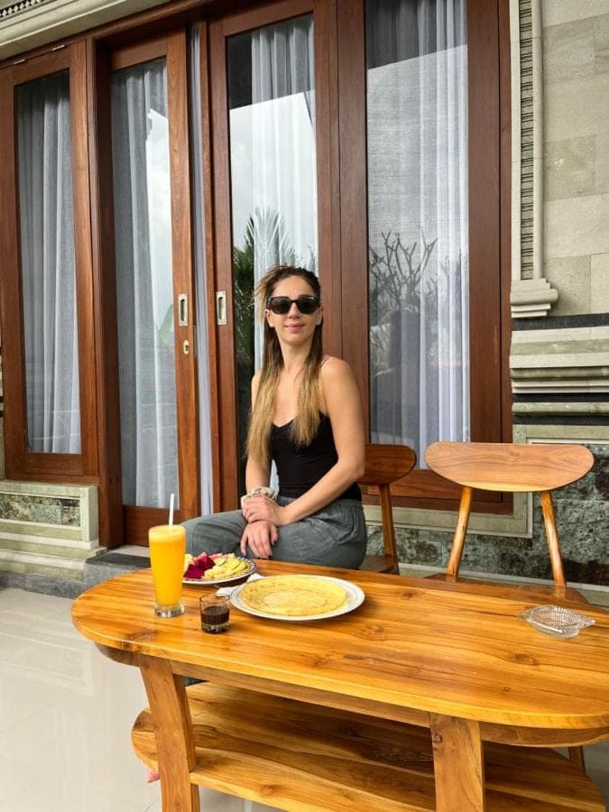 a woman sitting at a table with a plate of food at Krisna Double House in Sidemen
