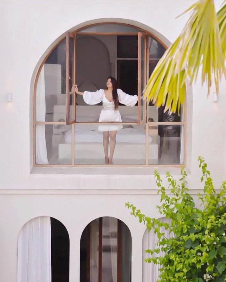 a woman in a white dress standing in a window at Casa Viamo in Canggu