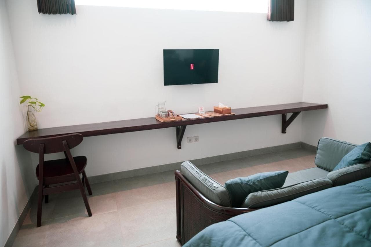 a living room with a couch and a tv on a wall at Sare Homestay and Artspace Sanur in Sanur