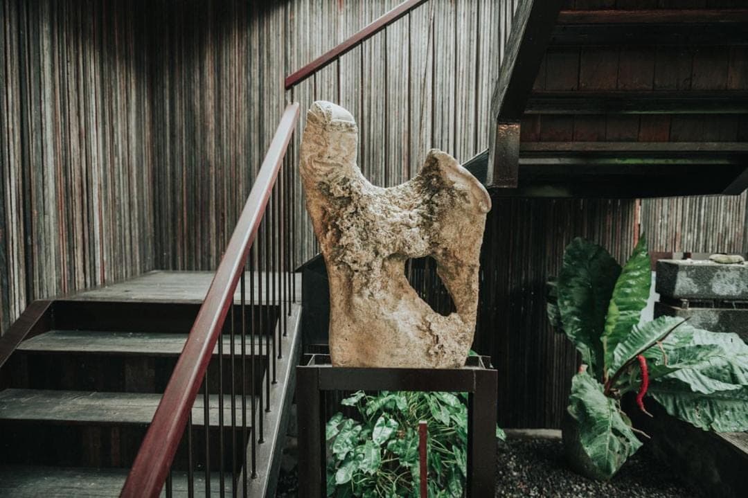 a statue sitting on the side of a staircase at Sare Homestay and Artspace Sanur in Sanur