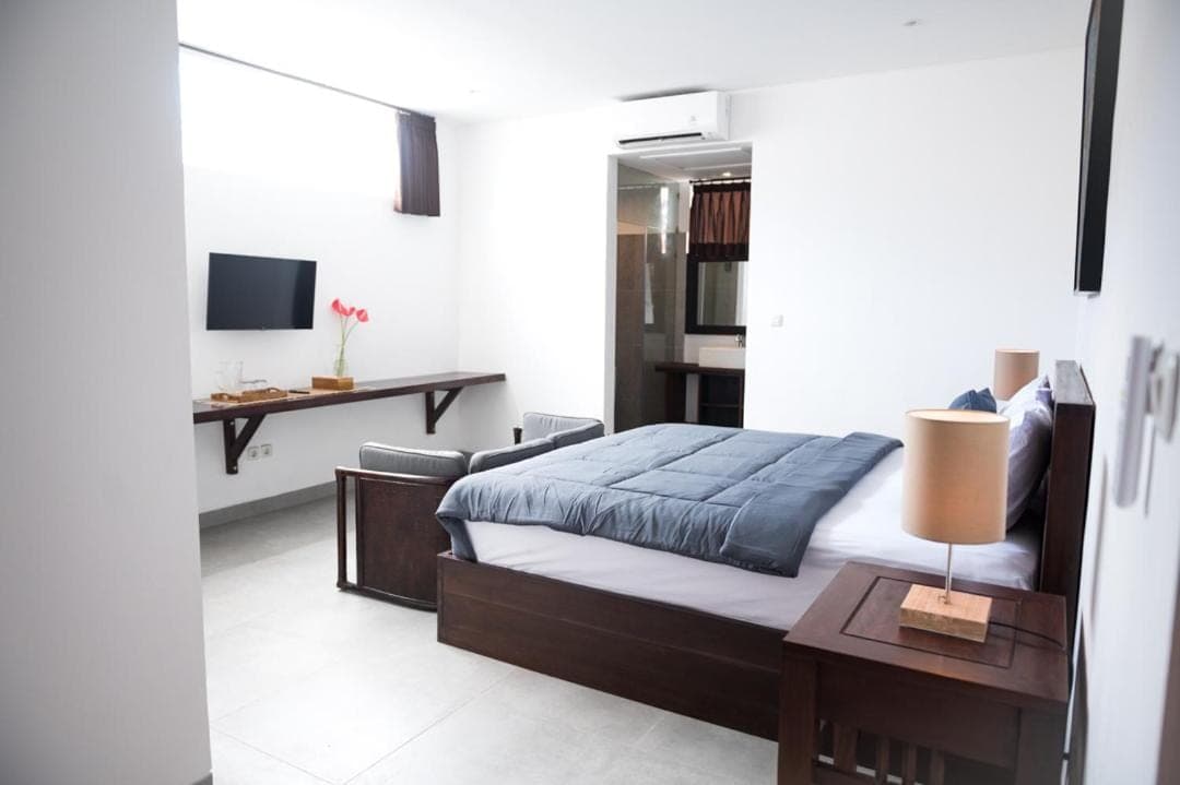 a bedroom with a bed and a table and a desk at Sare Homestay and Artspace Sanur in Sanur