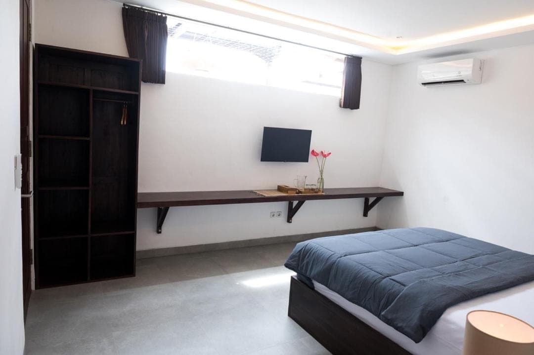 a bedroom with a bed and a desk with a computer at Sare Homestay and Artspace Sanur in Sanur
