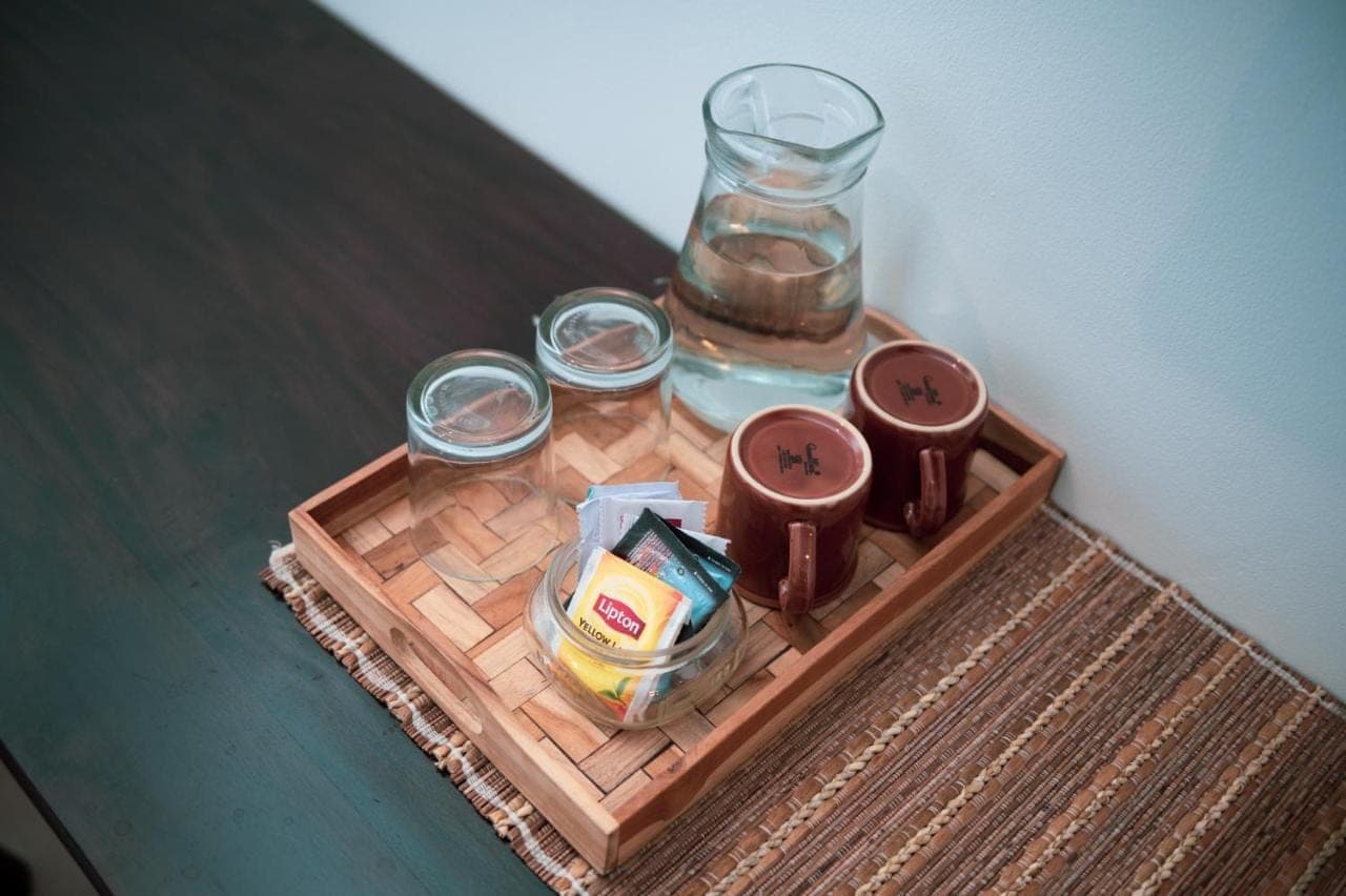 a table with a tray with a glass jar of water and a candle at Sare Homestay and Artspace Sanur in Sanur