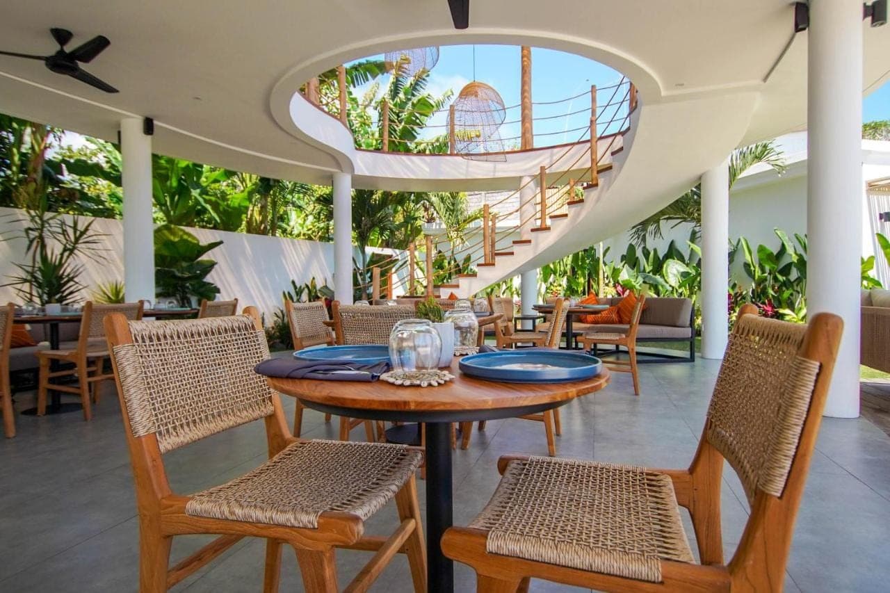 a restaurant with a table and chairs and a spiral staircase at Kalia Bingin - Adult only in Uluwatu