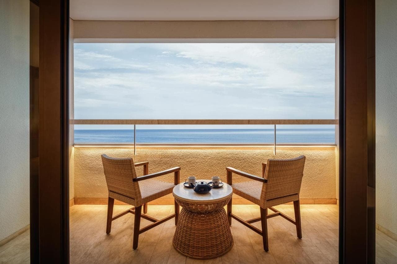 a balcony with a table and chairs and a view of the ocean at Bali Beach Hotel in Sanur
