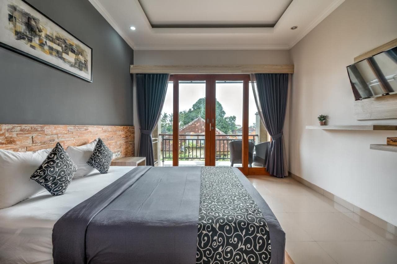 a bedroom with a large bed and a balcony at D Sarian Seminyak in Seminyak