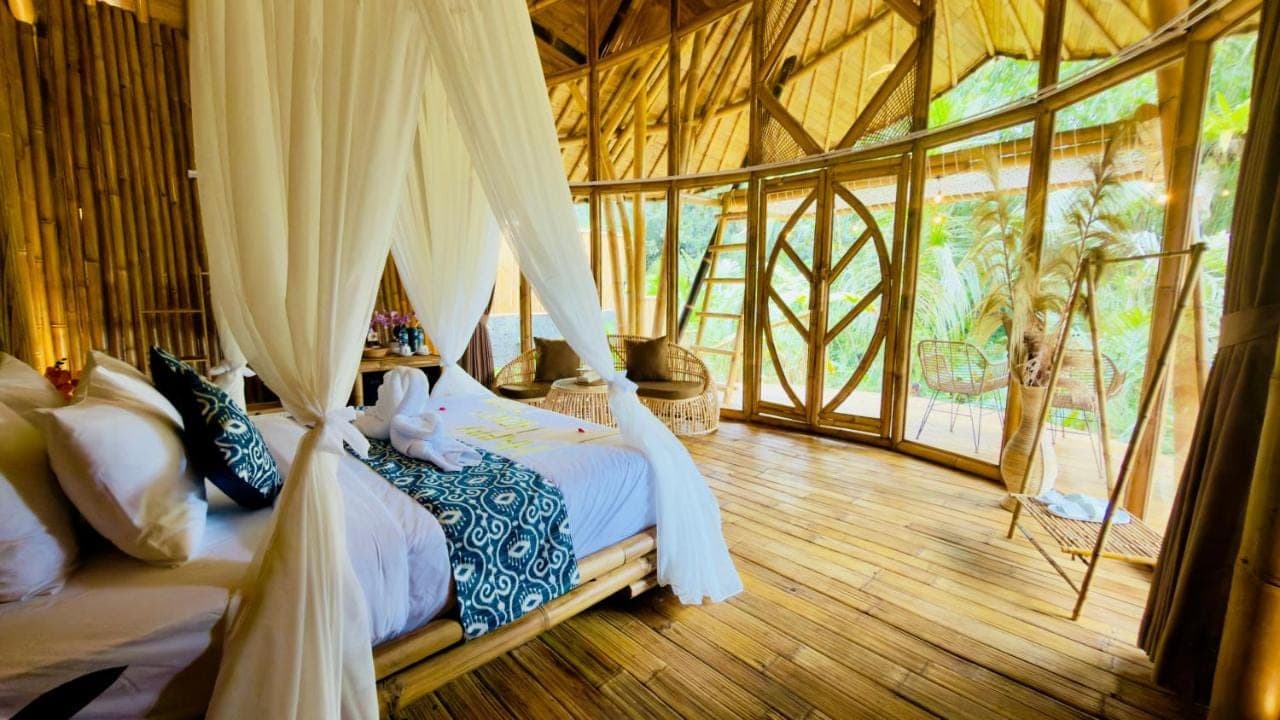 a bedroom with a bed in a room with windows at Phoenix Bamboo House by Ecobreeze in Sidemen