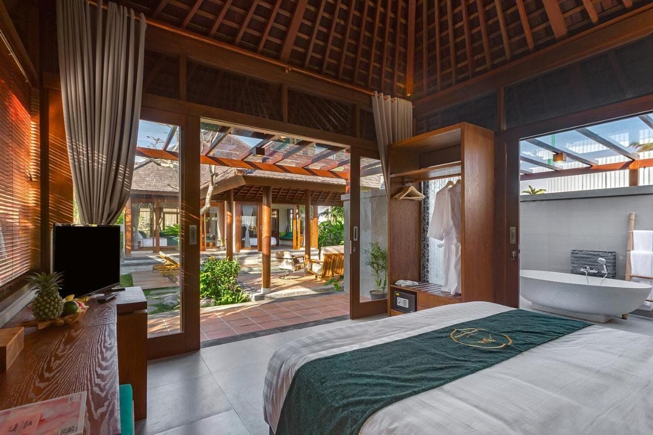 a bedroom with a bed and a tub and a television at Alam Wayang Ubud - CHSE Certified in Ubud