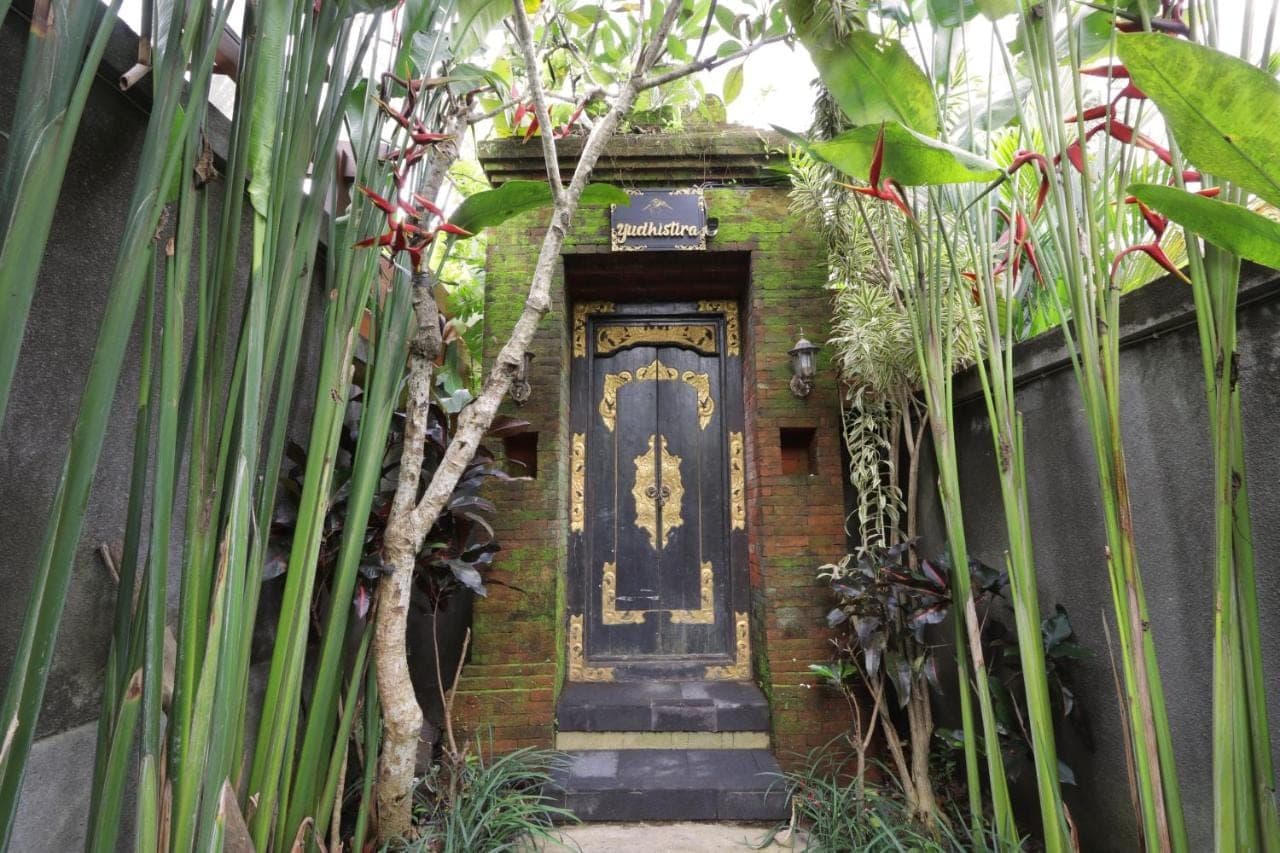a brick building with a blue door in a garden at Alam Wayang Ubud - CHSE Certified in Ubud