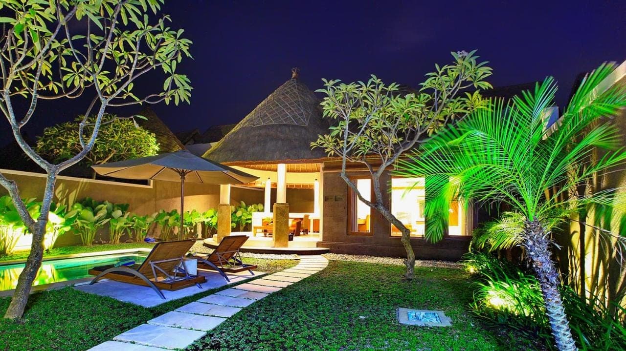 a house with two chairs and a swimming pool at night at Mutiara Bali Boutique Resort & Villa in Seminyak