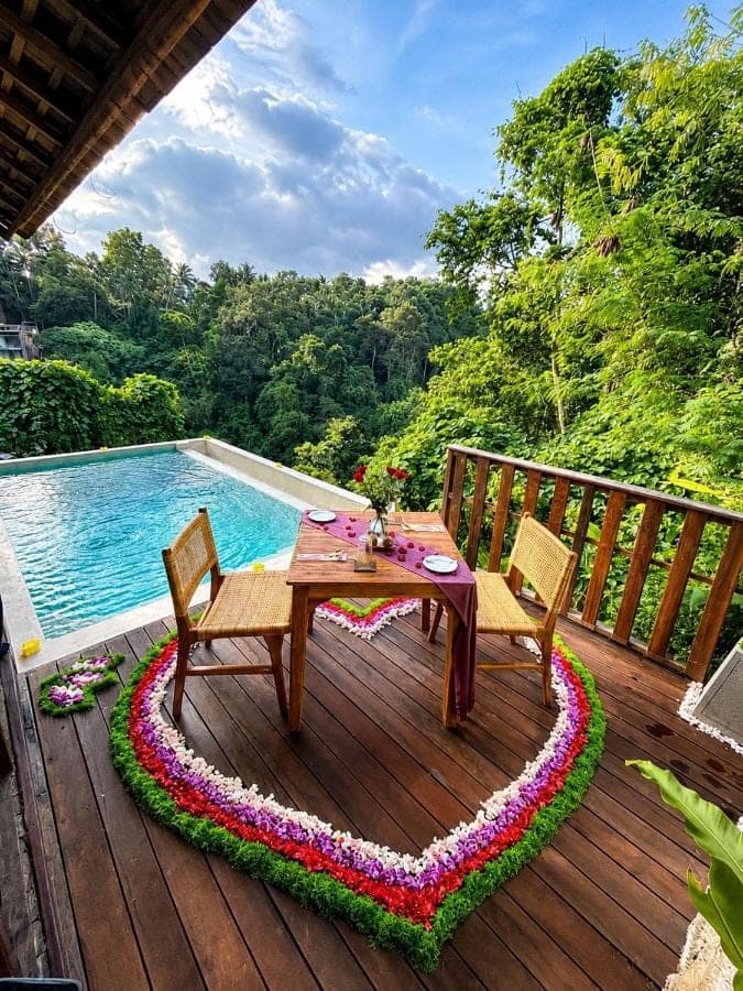a wooden deck with a table and chairs next to a pool at Les Mandarines - Rice fields & jungle retreat in Ubud