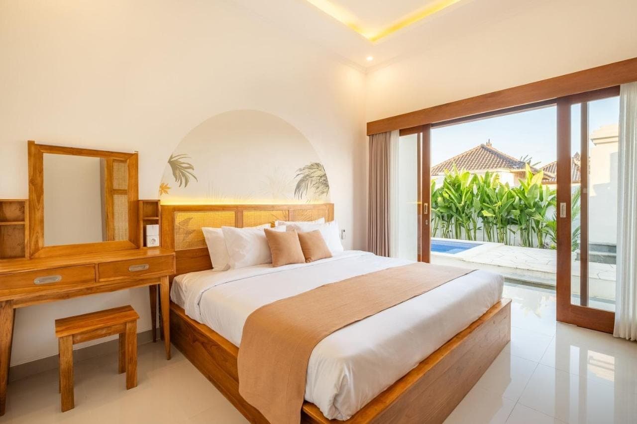 a bedroom with a bed and a mirror and a window at Cove D Ancak Villa and Bungalow in Nusa Dua