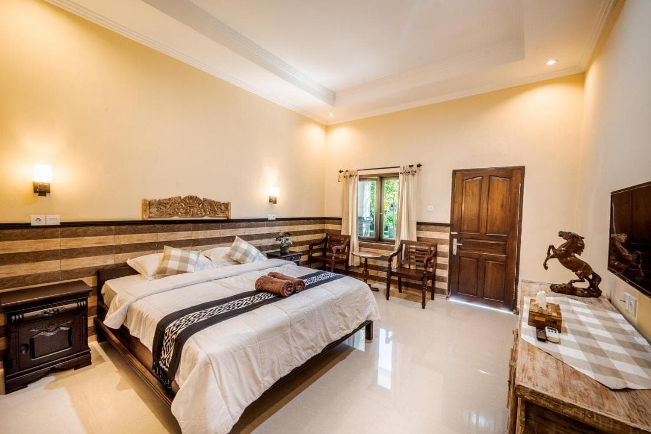 a bedroom with a large bed and a fireplace at Gria Umasari Sanur in Sanur