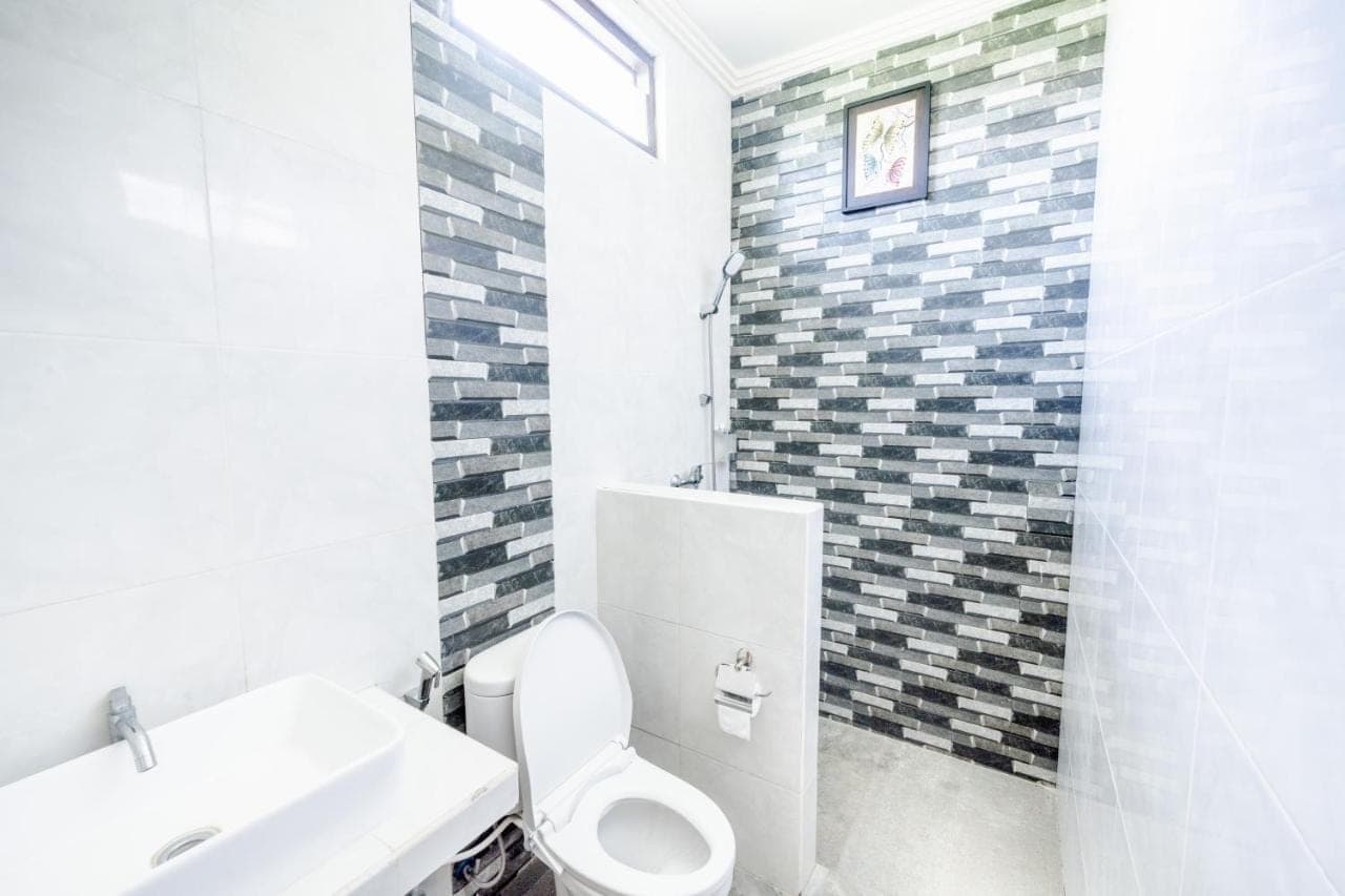 a white bathroom with a toilet and a sink at Gria Umasari Sanur in Sanur