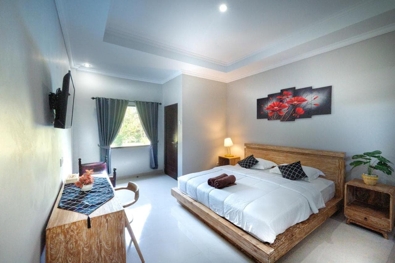 a bedroom with a bed and a table in it at Gria Umasari Sanur in Sanur