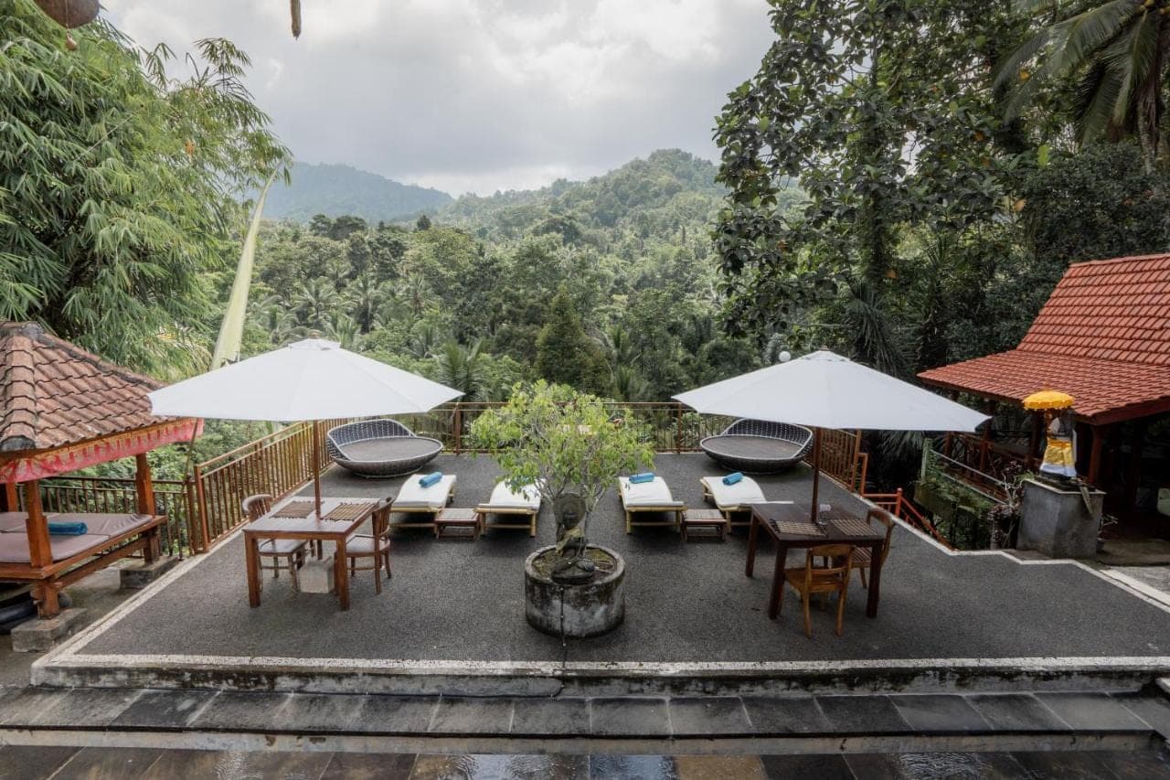 a patio with tables and chairs and umbrellas at Astana Swaha Villa in Sidemen