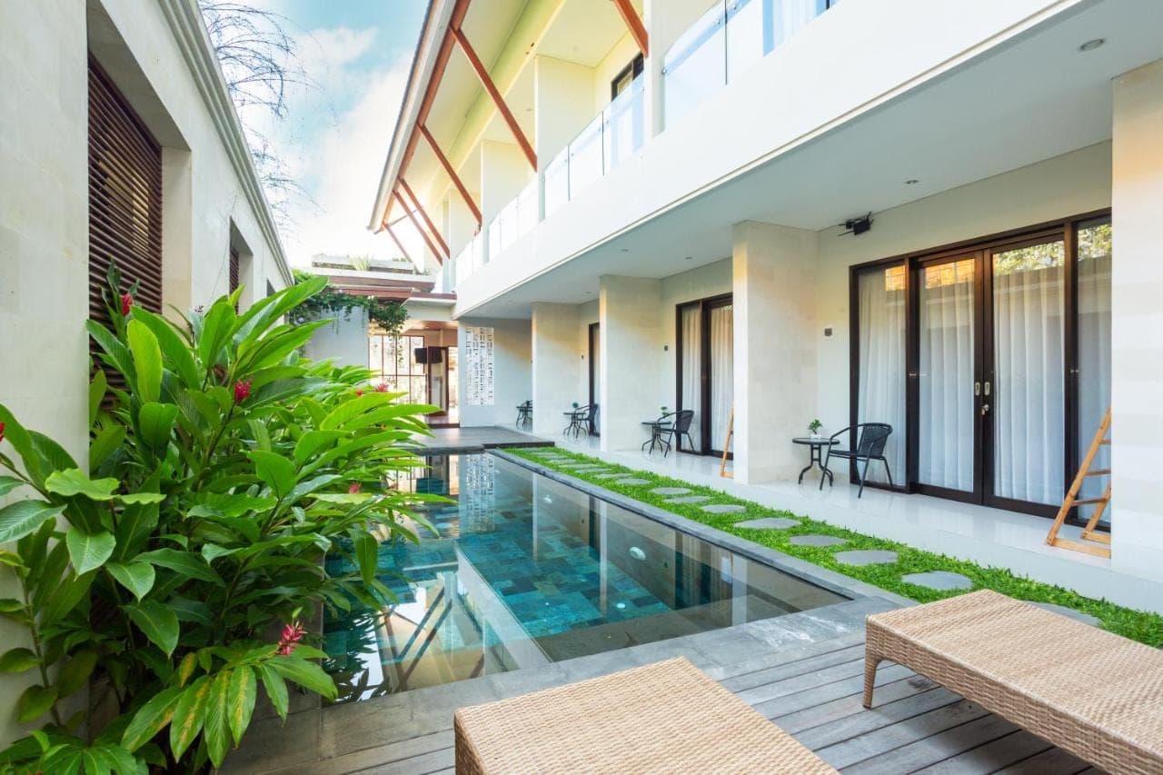 an indoor courtyard with a swimming pool in a house at Cove Ransha Stay in Sanur