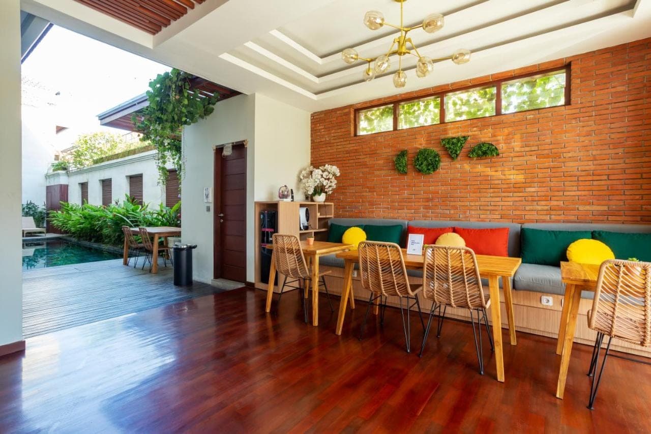 a dining room with a brick wall and a table and chairs at Cove Ransha Stay in Sanur