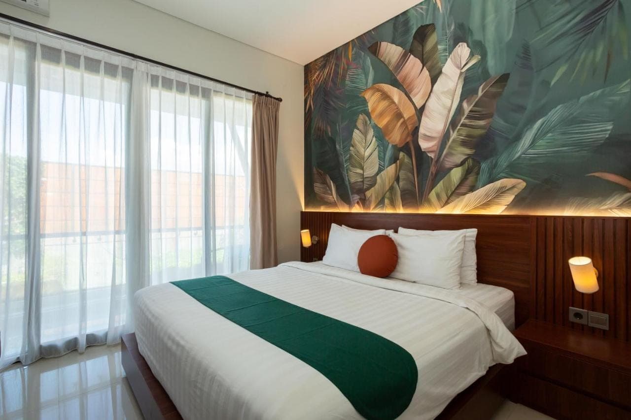 a bedroom with a large bed with a painting on the wall at Cove Ransha Stay in Sanur