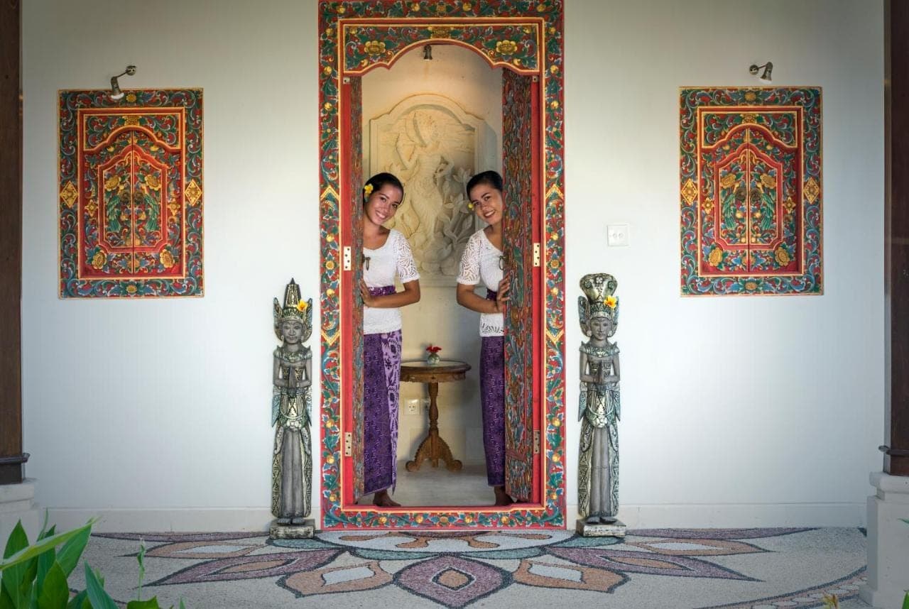 two women standing in front of a mirror at Palm Garden Amed Beach & Spa Resort Bali in Amed